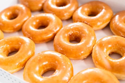 Plain glazed store-bought doughnuts in a white paper box.