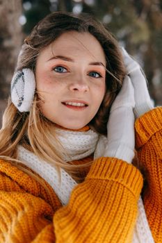 Teen blonde in a yellow sweater outside in winter. A teenage girl on a walk in winter clothes in a snowy forest.