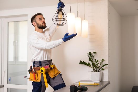 Electrician worker installation electric lamps light inside apartment. Construction decoration concept