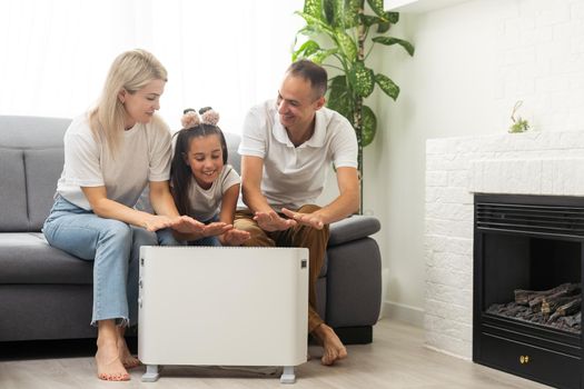 Family warming up near home heater at winter cold time. The symbolic image of the heating season at home