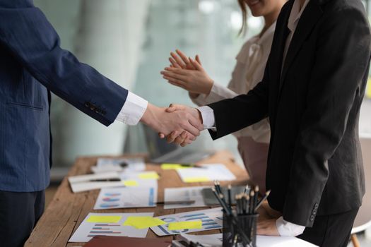 Group business people handshake at meeting table in office together with confident shot from top view . Young businessman and businesswoman workers express agreement of investment deal.