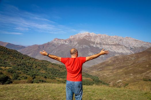 A man stands on top of a mountain with his arms outstretched