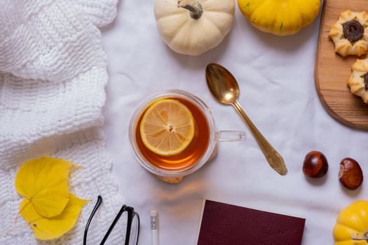 Cup of tea and autumn cozy decor with sweater and pumpkins top view.