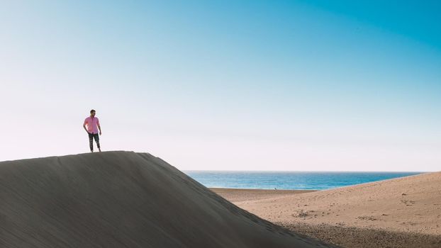 Young men walking at the beach of Maspalomas Gran Canaria Spain, young men walking in de sand during sun rise in the desert of Maspalomas Gran Canaria