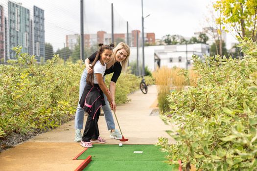 little girl and mother playing mini golf.