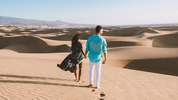 couple walking at the beach of Maspalomas Gran Canaria Spain, men and woman at the sand dunes desert of Maspalomas Gran Canaria