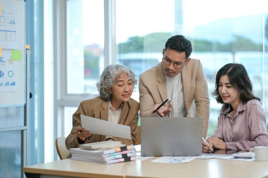 group of four happy young asian corporate executives working together meeting in office discussing business in office..