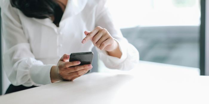 Closeup image of a beautiful asian woman holding , using and looking at smart phone.