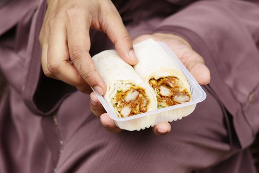 women eating chicken warp sitting on park bench, take out food concept ,