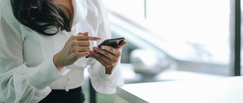 Closeup image of a beautiful asian woman holding , using and looking at smart phone.