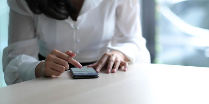 Closeup image of a beautiful asian woman holding , using and looking at smart phone.