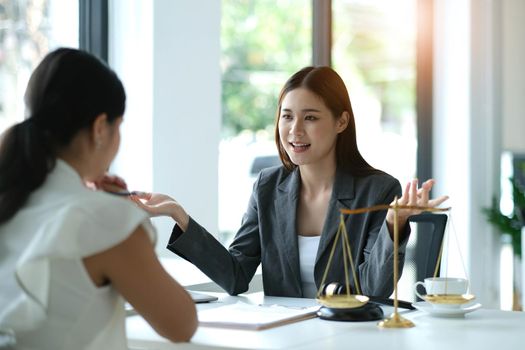 Business woman and lawyers discussing contract papers with brass scale on wooden desk in office. Law, legal services, advice, Justice concept.