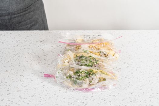 Packaging homemade frozen shrimp scampi meal prep into plastic resealable bags.