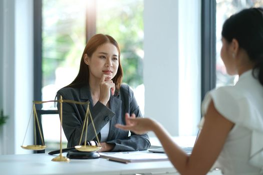 Business woman and lawyers discussing contract papers with brass scale on wooden desk in office. Law, legal services, advice, Justice concept.