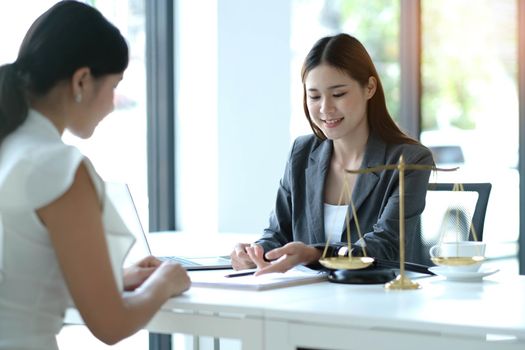 Business woman and lawyers discussing contract papers with brass scale on wooden desk in office. Law, legal services, advice, Justice concept.