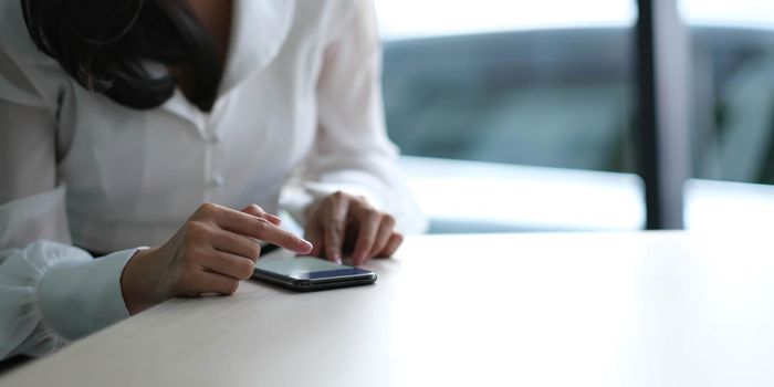 Closeup image of a beautiful asian woman holding , using and looking at smart phone.