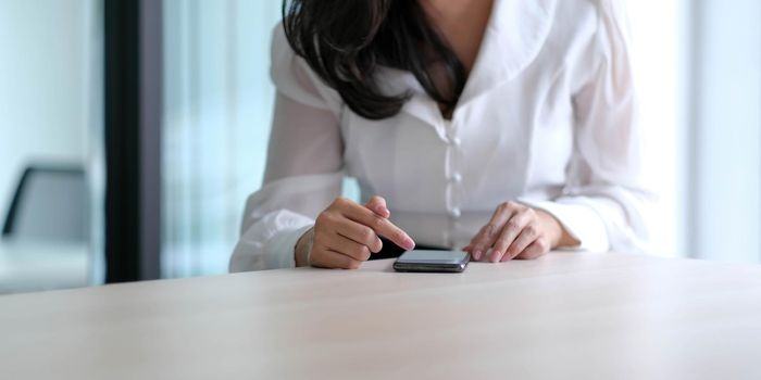 Closeup image of a beautiful asian woman holding , using and looking at smart phone.