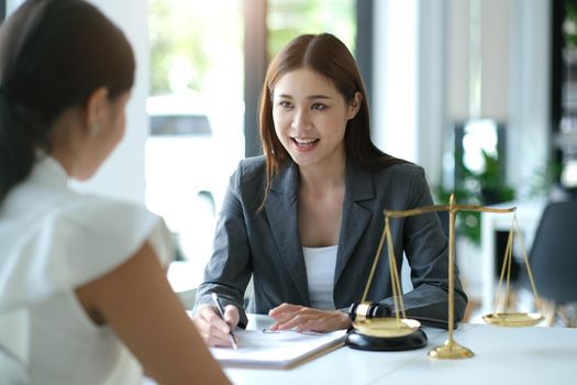 Business woman and lawyers discussing contract papers with brass scale on wooden desk in office. Law, legal services, advice, Justice concept.