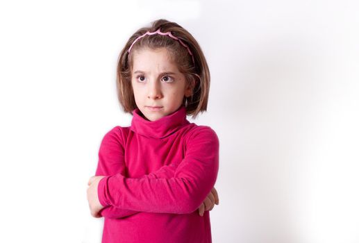 Cute upset little girl standing isolated over white background, looking away