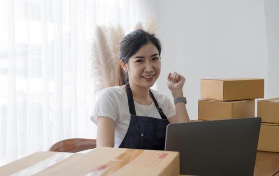 Portrait of Asian young woman SME working with a box at home the workplace.start-up small business owner, small business entrepreneur SME or freelance business online and delivery concept..