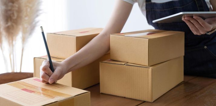 Portrait of Asian young woman SME working with a box at home the workplace.start-up small business owner, small business entrepreneur SME or freelance business online and delivery concept..