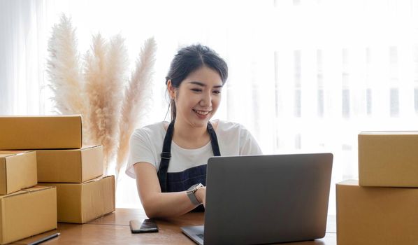 Starting small businesses SME owners female entrepreneurs Use a laptop or notebook to receive and review orders online to prepare to pack boxes, sell to customers, SME online business ideas..