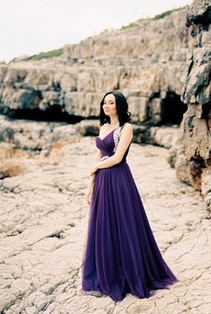 Woman in a long dress stands near the rocks. High quality photo