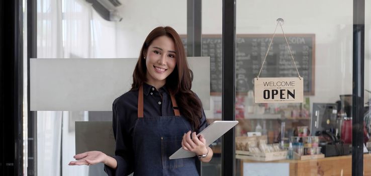 Startup successful small business owner sme beauty girl stand with tablet smartphone in coffee shop restaurant. Portrait of asian tan woman barista cafe owner. SME entrepreneur seller business concept.