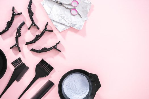 Flat lay. Hair color dye powder in a black plastic mixing bowl on a pink background.