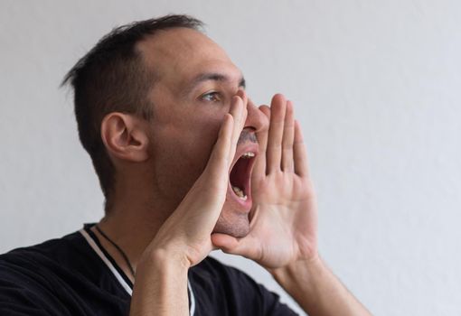 Handsome happy man wearing T-shirt, guy speaking loudly, isolated on white background.