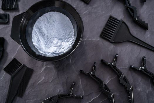 Hair color dye powder in a black plastic mixing bowl on a black background.