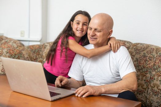 Grandfather adult granddaughter spend time together use laptop, browse website, younger generation teach explain to older how to use modern tech concept.