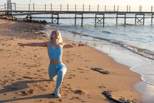 Young beautiful sportive girl training at sunrise over seaside