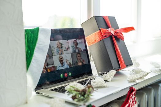 A happy family with a child is celebrating Christmas with their friends on video call using webcam. Family greeting their relatives on Christmas eve online. New normal virtual event