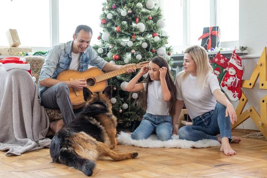 happy family and cute dog having fun at christmas tree. atmospheric emotional moments. merry christmas and happy new year concept