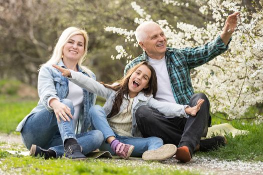 grandfather with granddaughter and daughter in spring, senior man in the yard.