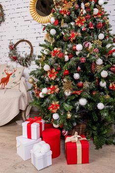 Beautiful Christmas gift boxes with red ribbon and pine cones on the table near the tree in the room