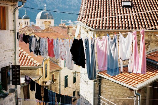 Multi-colored linen hangs on ropes between old houses. Kotor, Montenegro. High quality photo