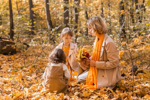 Young mother with her little daughter in an autumn park. Fall season, parenting and children concept