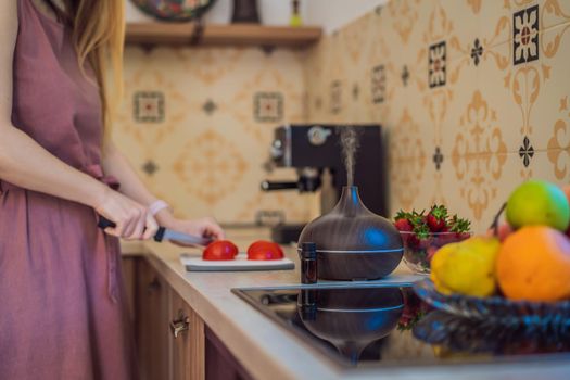 Woman prepares food next to an aroma diffuser. cook cuts ripe red peppers in the kitchen. Cooking fresh, ripe, bell pepper salad for guests. Summer fresh vegetable salad.