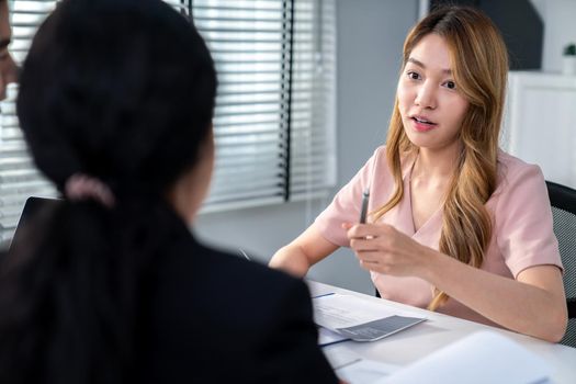 A young female asian candidate tries to impress her interviewer by being competent. International company, multicultural environment in workplace.