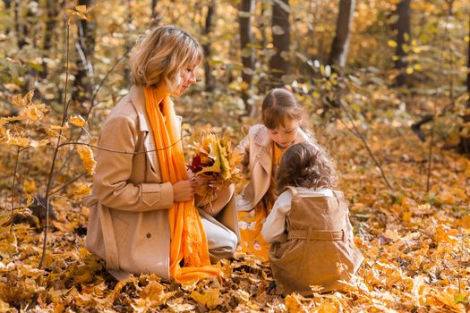 Young mother with her little daughter in an autumn park. Fall season, parenting and children concept
