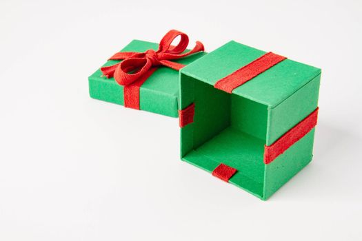 Present. Gift box with a bow. New Year's surprise. Red and green box with a gift. On a white background, top view. Close-up. Tied with a beautiful ribbon for gifting. Under the tree.