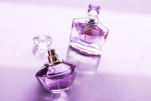 Perfumery, spa and branding concept - Purple perfume bottle on glossy background, sweet floral scent, glamour fragrance and eau de parfum as holiday gift and luxury beauty cosmetics brand design