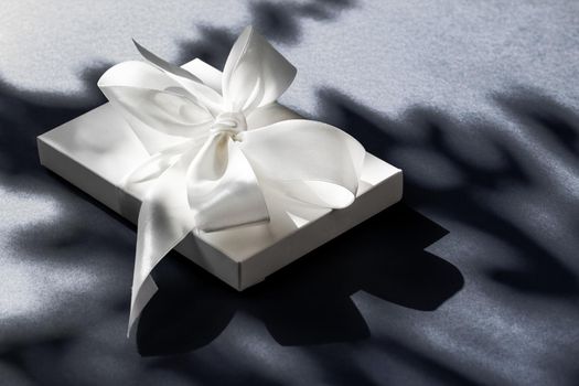 Anniversary celebration, shop sale promotion and luxe surprise concept - Luxury holiday white gift box with silk ribbon and bow on black background, luxe wedding or birthday present