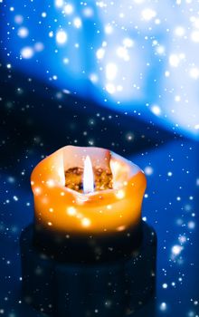 Happy holidays, greeting card and winter season concept - Yellow holiday candle on blue sparkling snowing background, luxury branding design for Christmas, New Years Eve and Valentines Day