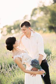 Groom leaned bride over the lavender field hugging her. High quality photo