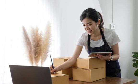 Portrait of Asian young woman SME working with a box at home the workplace.start-up small business owner, small business entrepreneur SME or freelance business online and delivery concept..