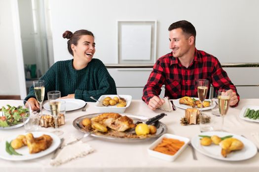 Happy, smiling young caucasian couple in love during Christmas family gathering. Christmas meal. Holiday concept.