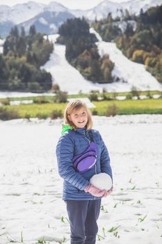 blonde girl makes a snowman in Slovenia in the Alps.
